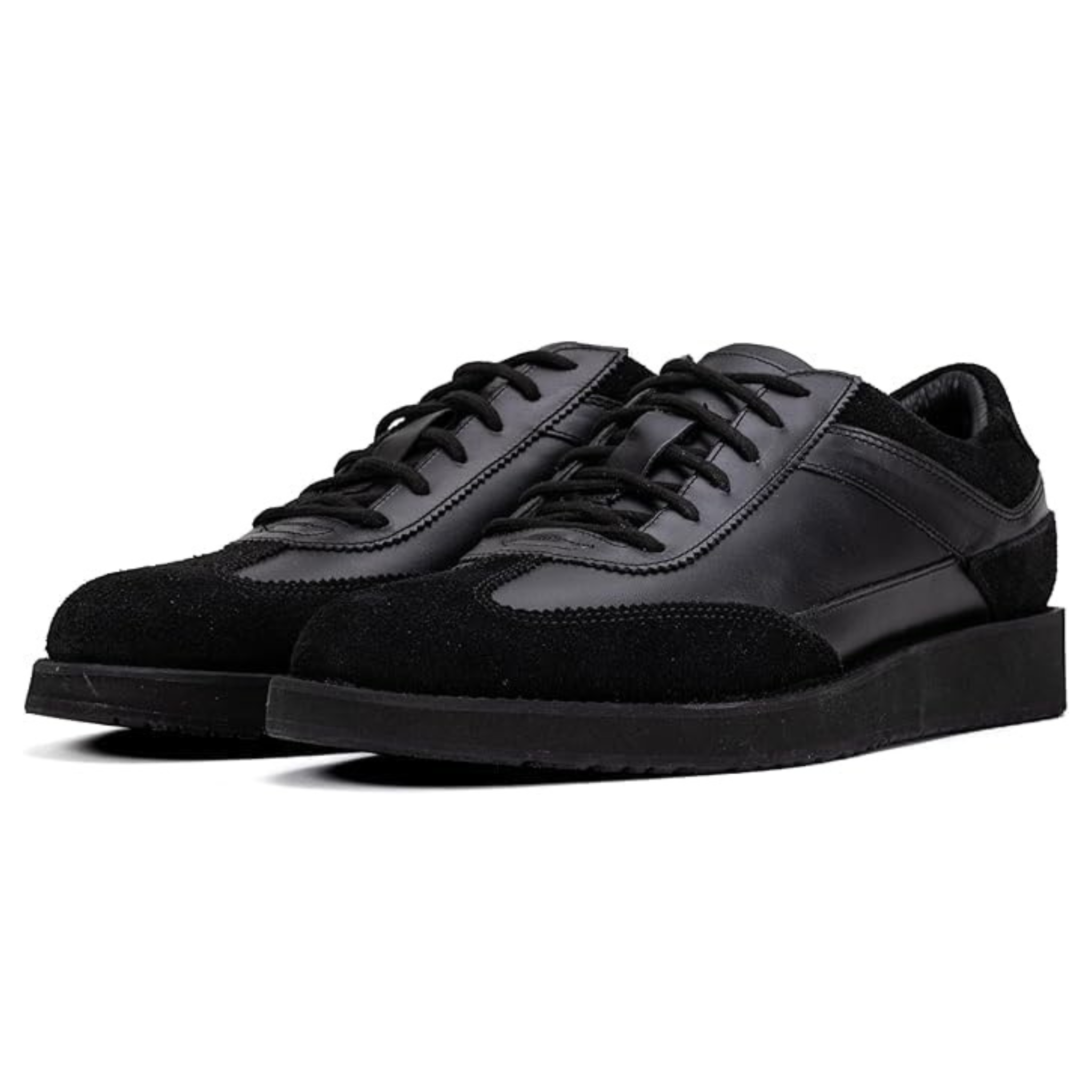 A pair of black suede leather semi-formal trainers with a lace-up closure and a thick sole.