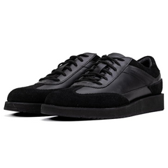 A pair of black suede leather semi-formal trainers with a lace-up closure and a thick sole.