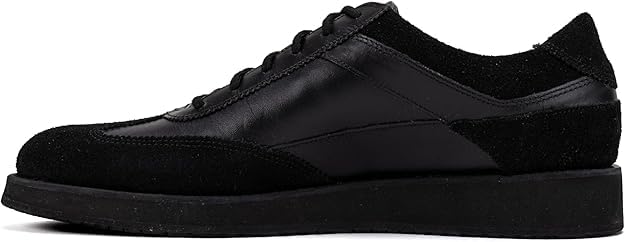 A pair of black suede leather semi-formal trainers with a lace-up closure and a thick sole.