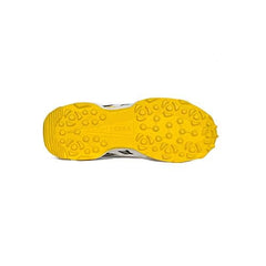 A pair of white cricket shoes with yellow accents and a distinctive design on the sole.