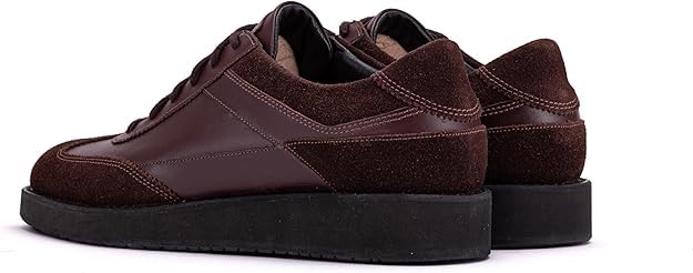 A pair of brown suede leather semi-formal trainers with a lace-up closure and a thick sole.