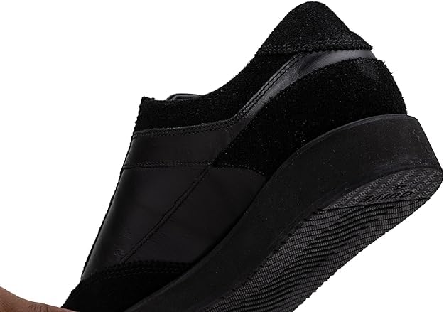 A pair of black suede leather semi-formal trainers with a lace-up closure and a thick sole.