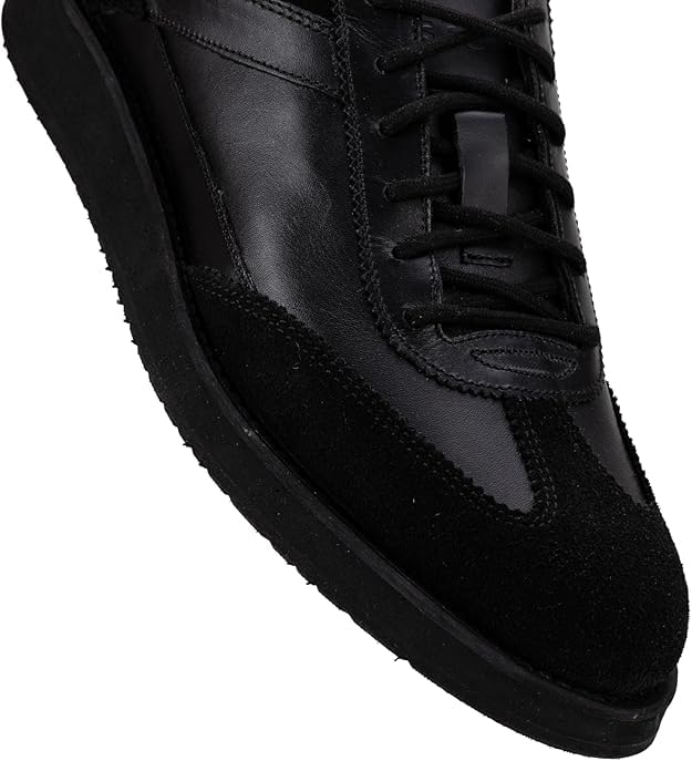 A pair of black suede leather semi-formal trainers with a lace-up closure and a thick sole.