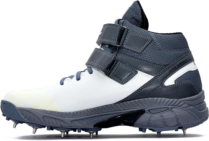 A pair of white, and grey cricket bowling shoes with metal spikes and an external strap for support.