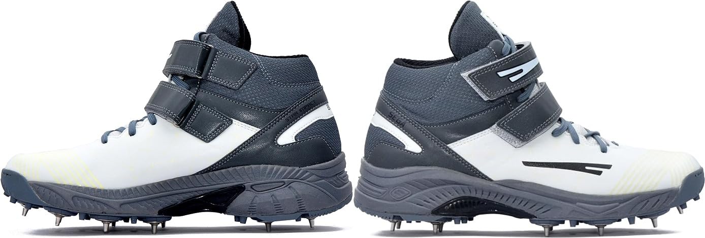 A pair of white, and grey cricket bowling shoes with metal spikes and an external strap for support.