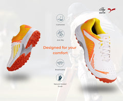 A pair of white, and orange cricket shoes with rubber studs and an lace up for support.