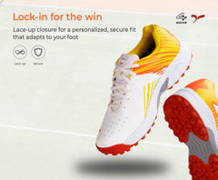 A pair of white, and orange cricket shoes with rubber studs and an lace up for support.