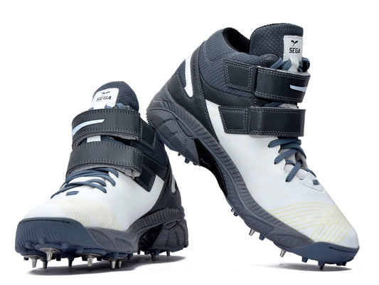 A pair of white, and grey cricket bowling shoes with metal spikes and an external strap for support.