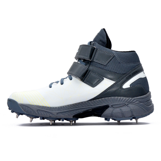 A pair of white, and grey cricket bowling shoes with metal spikes and an external strap for support.