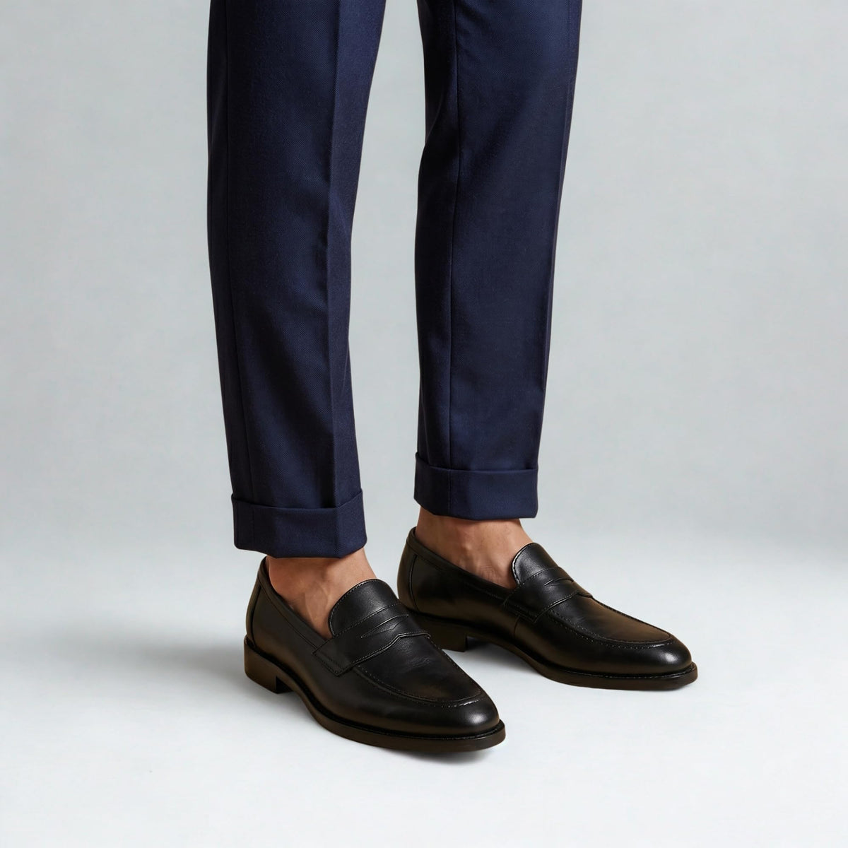 Black QUIVE London Ventor penny loafers worn with navy trousers
