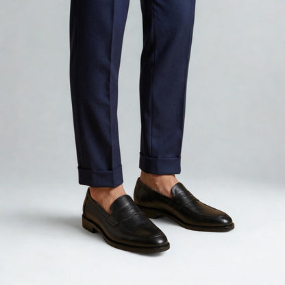 Black QUIVE London Ventor penny loafers worn with navy trousers