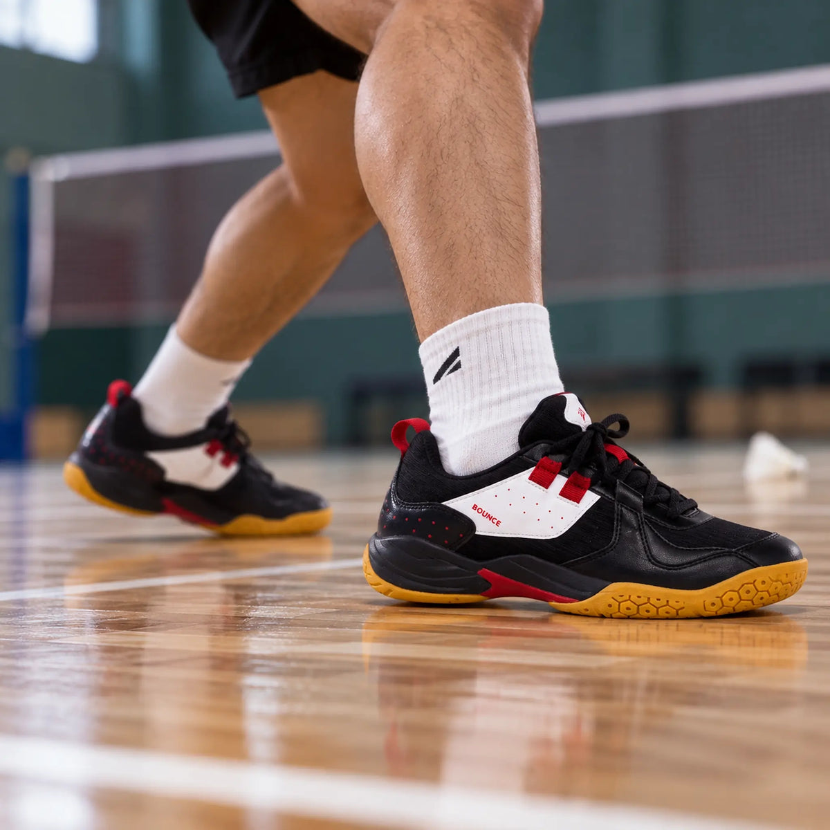Black QUIVE Bounce court shoes worn during an indoor badminton drill