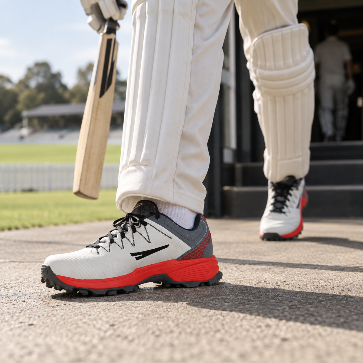 White and red QUIVE G-Power cricket shoes worn leaving a cricket pavilion