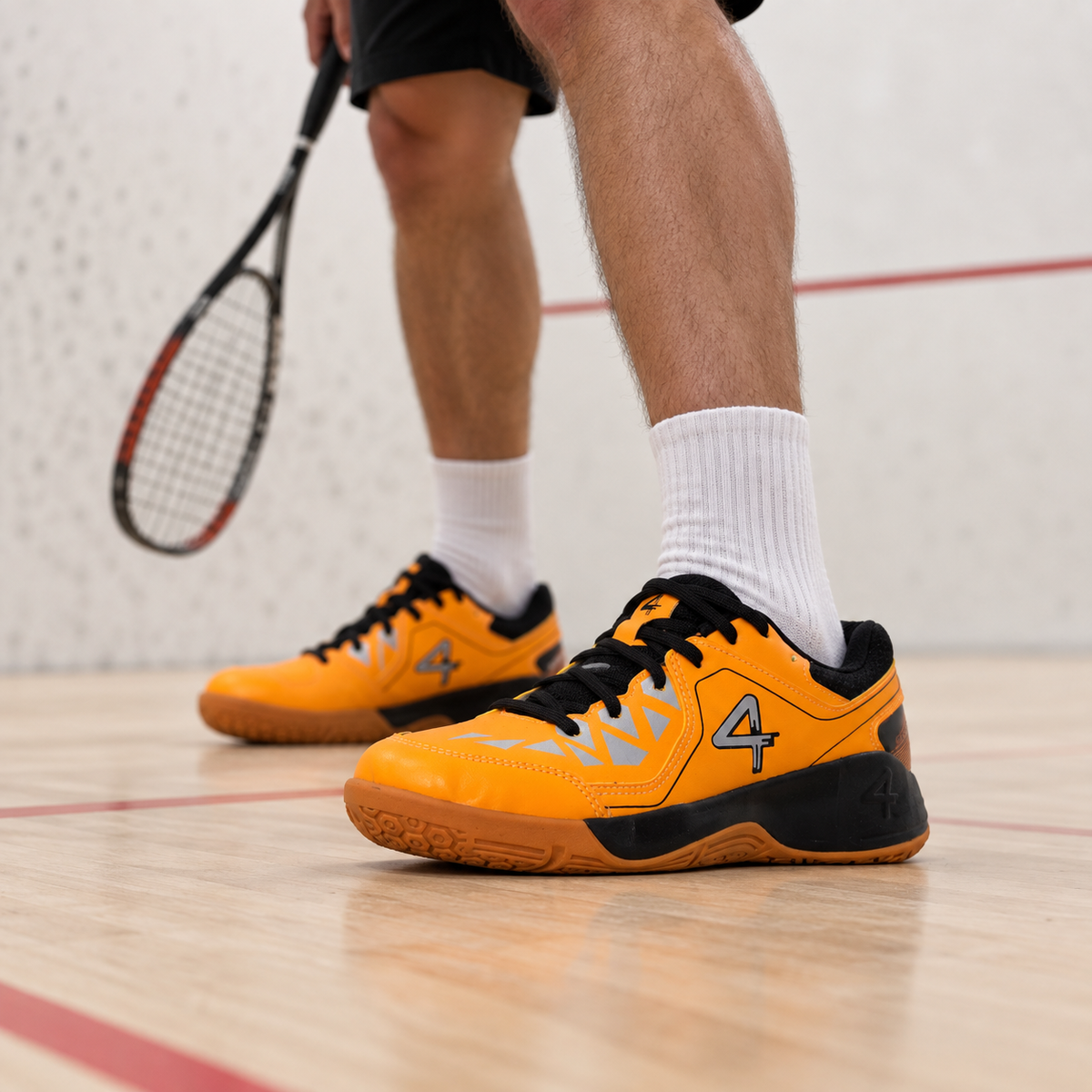 Orange QUIVE Hyper court shoes worn on an indoor squash court