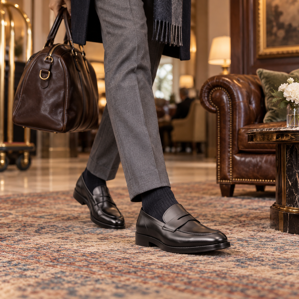 QUIVE Regent black leather penny loafers worn in an elegant hotel lounge