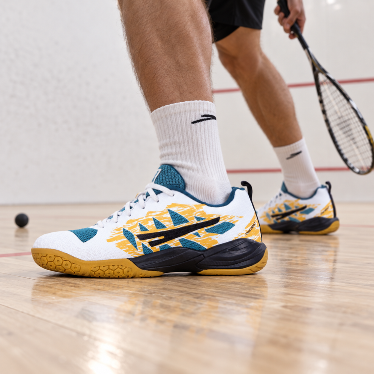 White teal and gold QUIVE RP24 court shoes worn on a squash court
